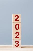 bloco de cubo de madeira com texto de 2023 no fundo da mesa. resolução, plano, revisão, objetivo, conceitos de férias de início e ano novo foto