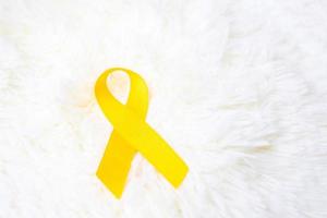 fita amarela sobre fundo branco para apoiar pessoas vivas e doentes. setembro dia de prevenção ao suicídio, mês de conscientização do câncer infantil e conceito de dia mundial do câncer foto