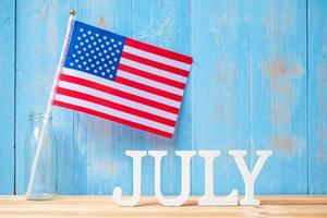 texto de julho e bandeira dos estados unidos da américa no fundo da mesa de madeira. feriado dos eua de conceitos de independência e celebração foto