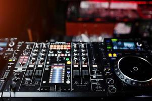 DJ girando mixagem e arranhando controles de faixa no estroboscópio do deck do dj. conceito de vida de clube de música dj. foto