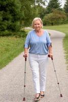 mulher de meia idade andando com dois bastões foto