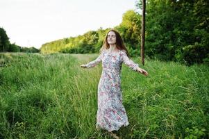 retrato de uma jovem fabulosa de vestido andando na grama alta. foto