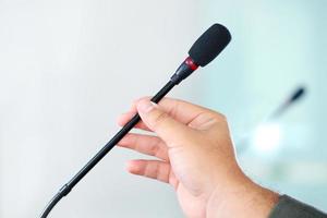 mão segurando o microfone de conferência na sala de reuniões