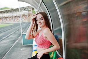 garota desportiva de fitness em roupas esportivas em esportes ao ar livre do estádio. mulher sexy feliz na tribuna do treinador. foto