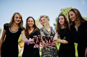 cinco garotas usam preto com balões bebendo champanhe vermelho na festa de despedida. foto