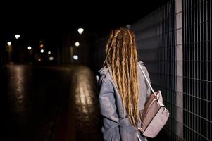 menina com dreadlocks andando na rua à noite da cidade. foto