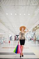 retrato de uma jovem atraente em blusa de leopardo, saia preta posando com um chapéu e sacolas de compras. foto
