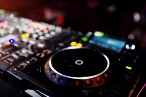 DJ girando mixagem e arranhando controles de faixa no estroboscópio do deck do dj. conceito de vida de clube de música dj. foto