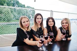 grupo de 4 meninas em preto com taças de champanhe na festa de despedida. foto