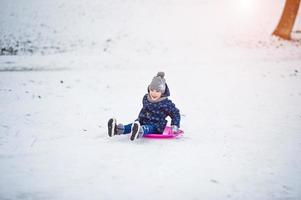 menina bonitinha com trenós pires ao ar livre em dia de inverno. foto