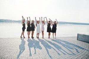 grupo de 7 meninas vestem preto e 2 noivas e fazem sombras na festa de despedida. foto