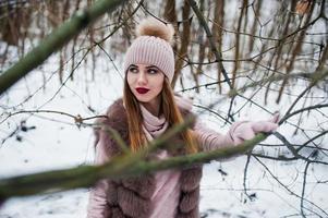 garota elegante com casaco de pele e chapéus na floresta de inverno. foto