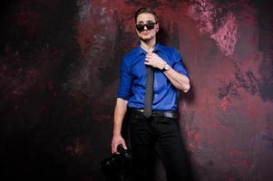 retrato de estúdio de homem elegante fotógrafo profissional com câmera, usar camisa azul e gravata, óculos de sol. foto