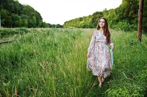 retrato de uma jovem fabulosa de vestido andando na grama alta. foto