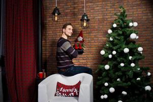 retrato de estúdio do homem contra a árvore de natal com enfeites. foto