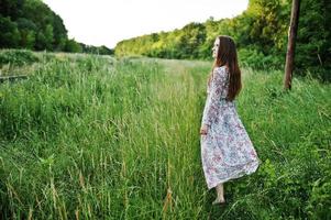 retrato de uma jovem fabulosa de vestido andando na grama alta. foto