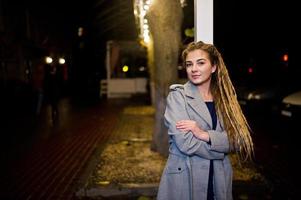 menina com dreadlocks andando na rua à noite da cidade. foto