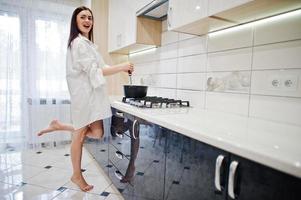 menina morena, use camiseta e cueca cozinhando na cozinha branca. foto