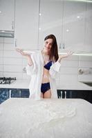 menina morena, usar camisa e cueca brincar com farinha na cozinha branca. foto