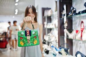 retrato de uma linda mulher de vestido cinza posando com bolsa verde vibrante. foto