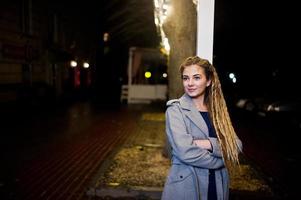 menina com dreadlocks andando na rua à noite da cidade. foto