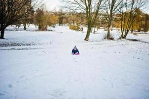 menina bonitinha com trenós pires ao ar livre em dia de inverno. foto