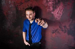 retrato de estúdio de homem elegante, use camisa azul e gravata, mostrando o dedo. foto