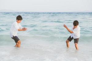 retrato homossexual jovem casal asiático joga água na praia com alegre juntos no verão, turismo da ásia gay diversão para lazer e relaxar com felicidade em férias no mar, conceito legal lgbt. foto