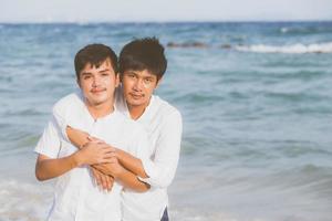 retrato homossexual jovem casal asiático abraço juntos na praia no verão, ásia gay indo turismo para lazer e relaxar com romântico e felicidade em férias no mar, conceito lgbt. foto