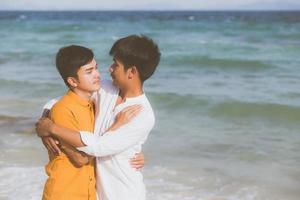 retrato homossexual jovem casal asiático abraço juntos na praia no verão, ásia gay indo turismo para lazer e relaxar com romântico e felicidade em férias no mar, conceito lgbt. foto