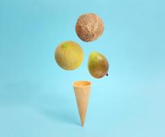 casquinha de sorvete com queda de coco, melão e manga. composição conceitual criativa em azul pastel foto