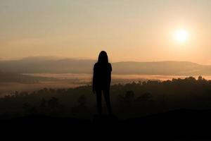 silhueta de menina olhando para o pôr do sol foto