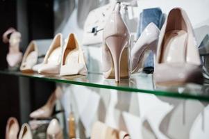 enorme variedade de sapatos femininos e bolsas de cores diferentes nas prateleiras da loja. foto
