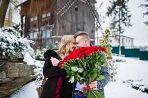 casal apaixonado no dia de inverno com grande buquê de 101 rosas. foto