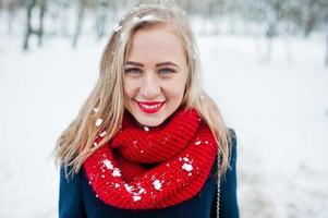 retrato de menina loira de cachecol vermelho e casaco em dia de inverno. foto