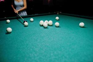 mulher de vestido jogando sinuca com um homem em um pub. foto