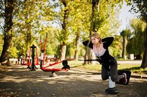 jovem tem o treinamento e exercício ao ar livre em simuladores de rua. esporte, fitness, conceito de treino de rua. foto