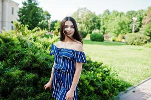 linda menina morena na rua da cidade usa vestido listrado azul. foto