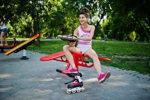 garota esportiva usar shorts brancos e camisa fazendo exercícios em simuladores ao ar livre no parque. foto