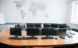 escritório de negócios durante o dia com muitas telas de computador. mapa na parede foto