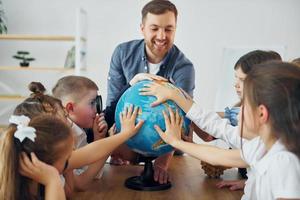 Aula de geografia com globo nas mãos grupo de alunos de crianças