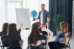 grupo de alunos de crianças em sala de aula na escola com professor foto