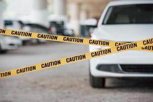 frente do veículo de luxo moderno. fita de advertência amarela perto do estacionamento durante o dia. cena do crime foto