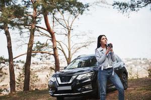 morena chegaram à floresta em seu novo carro preto foto