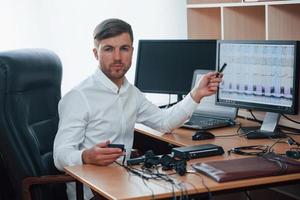 falando de resultados. examinador de polígrafo trabalha no escritório com o equipamento de seu detector de mentiras foto