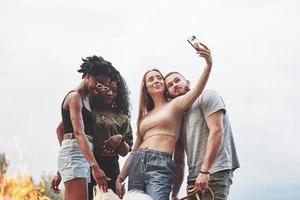 vamos fazer foto para memorizar este momento. grupo de pessoas faz piquenique na praia. amigos se divertem no fim de semana