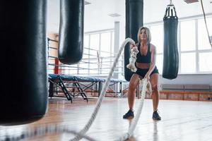 bonito e atlético. mulher loira esporte tem exercício com cordas no ginásio. mulher forte foto