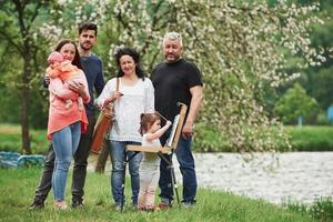 família se diverte no parque. jovem pintor ensinando a desenhar foto