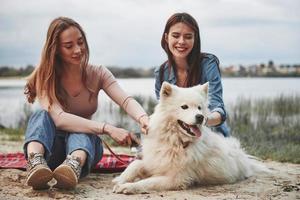 duas amigas se divertem na praia com cachorro fofo foto