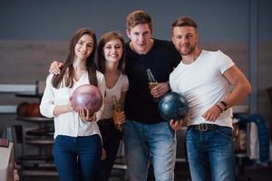 com álcool nas mãos. jovens amigos alegres se divertem no clube de boliche em seus fins de semana foto